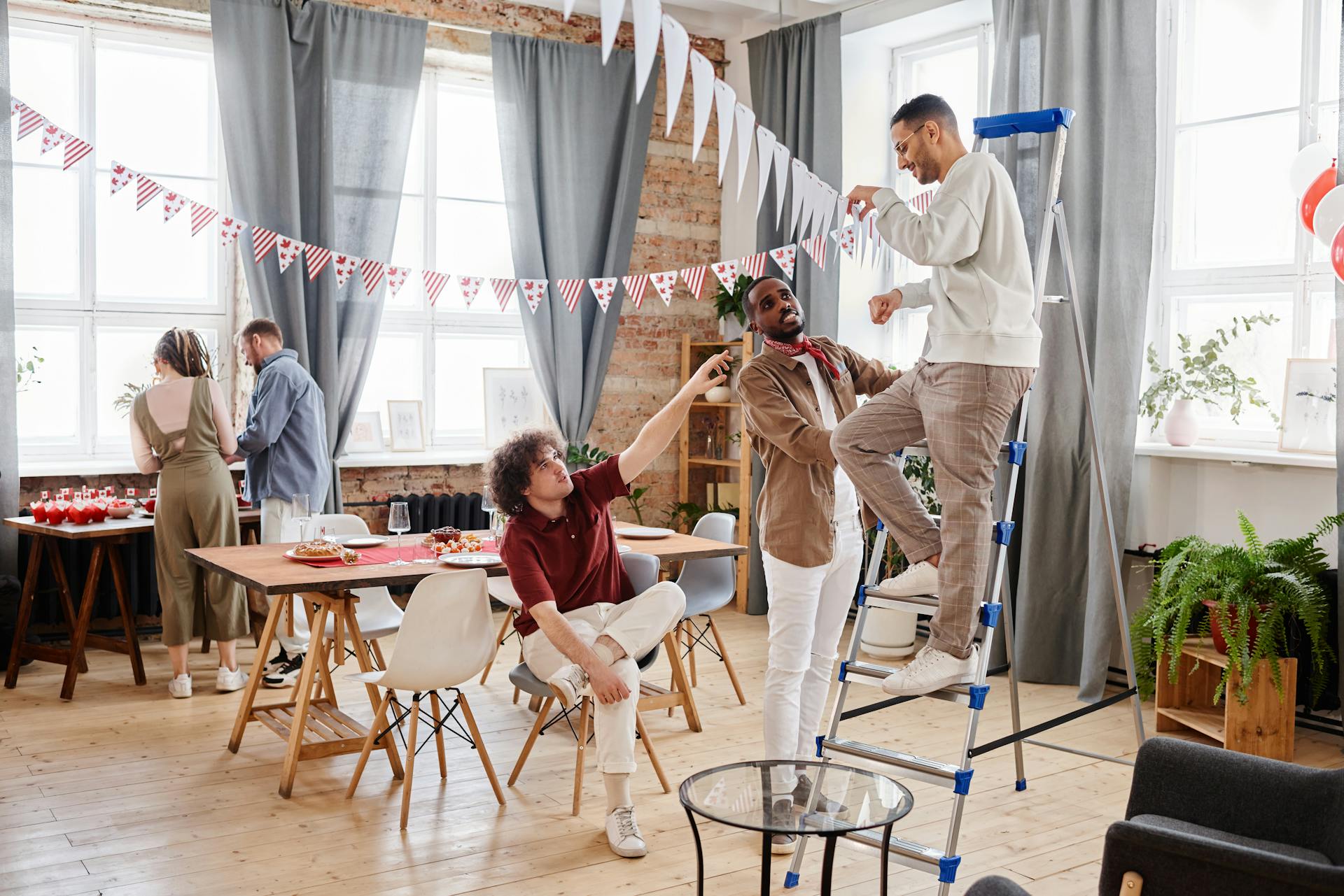 Group setting up decorations for a festive indoor party with banners and balloons.