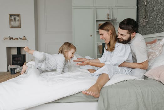 A joyful family morning with parents and child playing on a bed together.