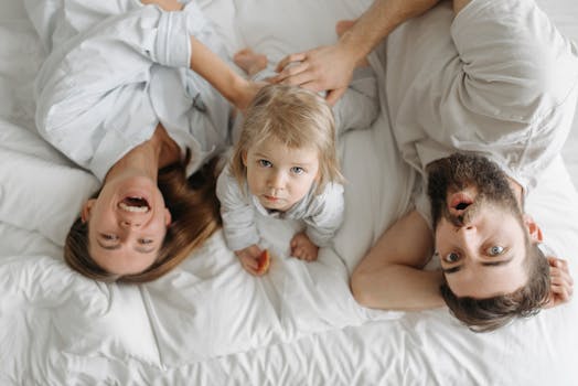 Playful family morning with parents and toddler in bed, embracing a joyful routine.