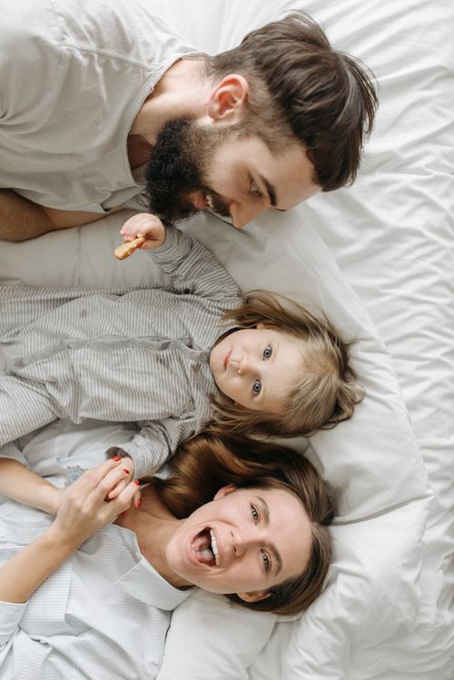 Free A happy family enjoying a relaxing morning together on a comfortable bed. Stock Photo
