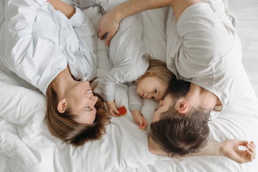 Father, mother, and daughter bonding on a bed, embracing family moments.