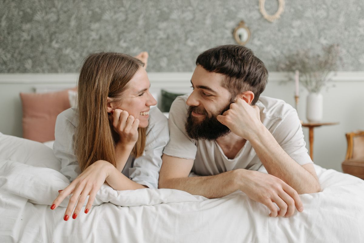 Happy couple smiling together in bed