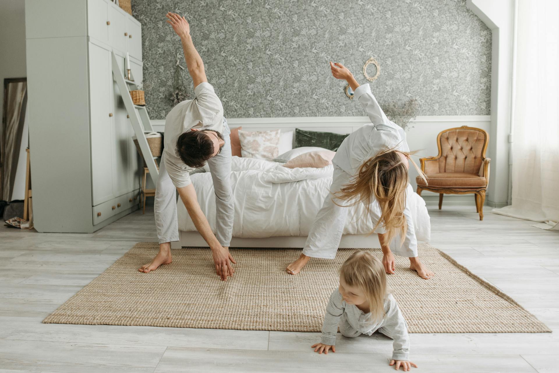 A Couple Stretching their Body Near Their Daughter Crawling on the Floor