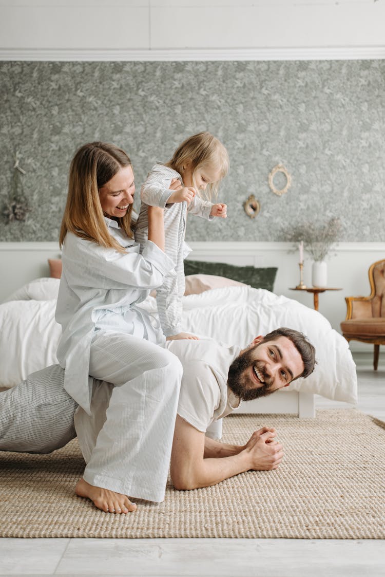 A Couple Spending Time With Their Daughter Inside The Bedroom