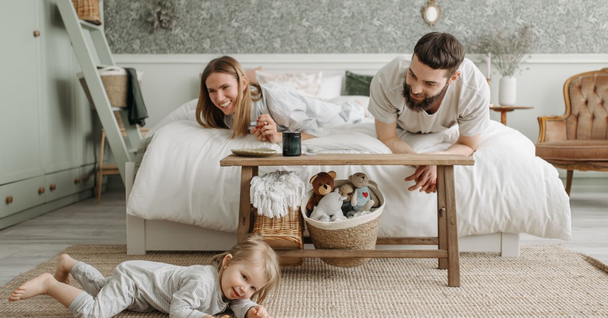 Une famille joyeuse se liant dans une chambre confortable, avec un enfant joueur et des parents aimants.