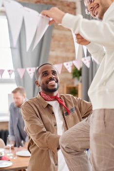 Group of friends joyfully hanging decorations indoors for a party or event.
