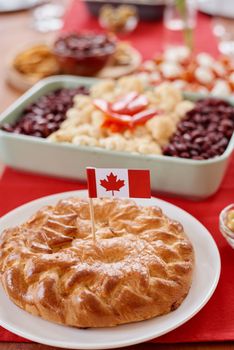 Golden pie with Canadian flag, surrounded by appetizers, perfect for celebrations.