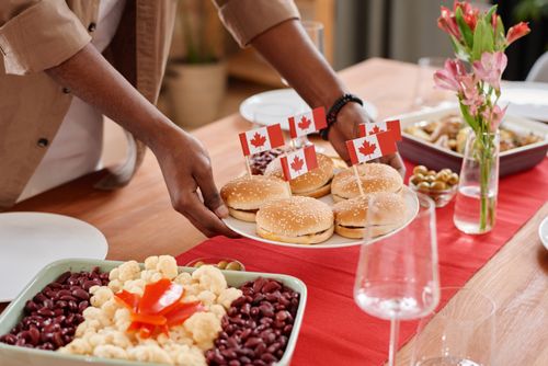 Free Celebrate Canada Day with delicious burgers adorned with flags, surrounded by a vibrant festive spread. Stock Photo