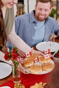 People enjoying a festive meal with Canadian themed burgers indoors.