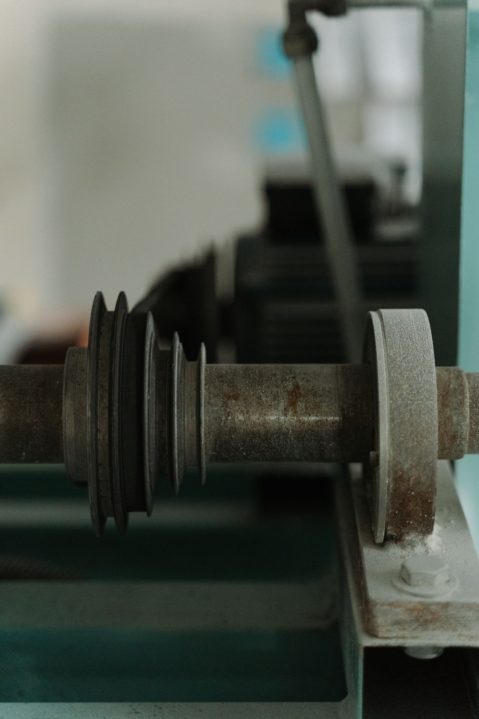 Detailed industrial machinery shaft and pulley in a workshop.