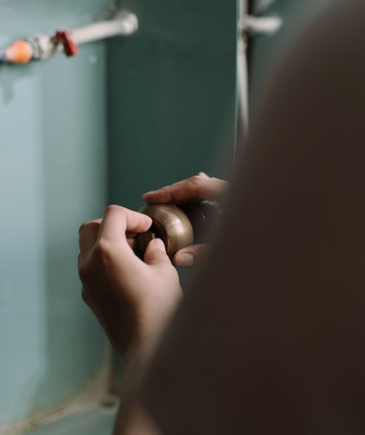 Hands fitting a pipe under a kitchen sink