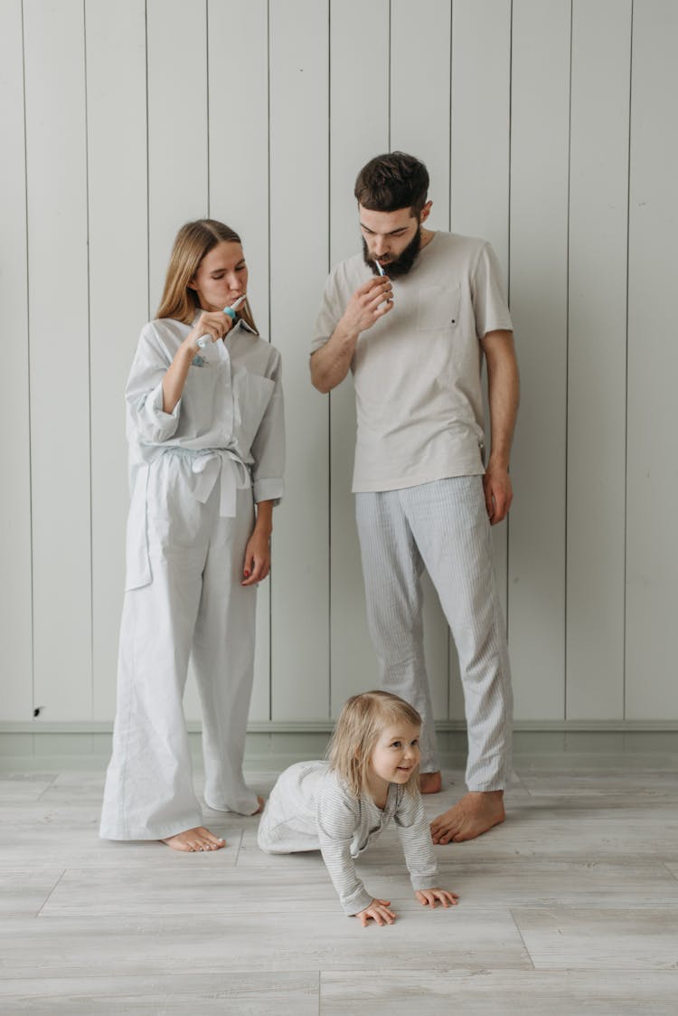 Man And Woman Standing Beside A Child While Brushing Teeth