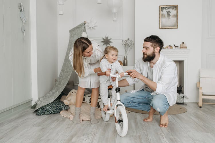 Photo Of A Kid Riding A Bike With Her Parents