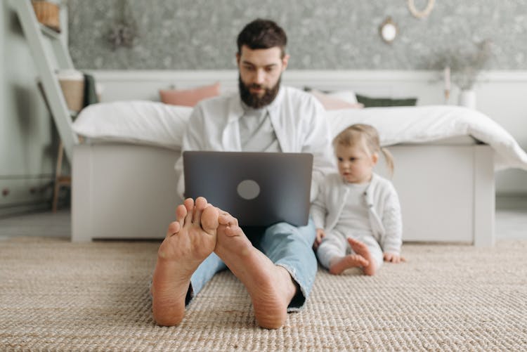 A Man Using A Laptop In The Bedroom