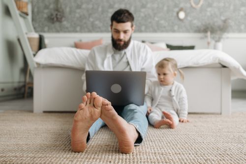 Free A father and daughter sitting on the floor with a laptop, enjoying quality time together in a cozy bedroom. Stock Photo