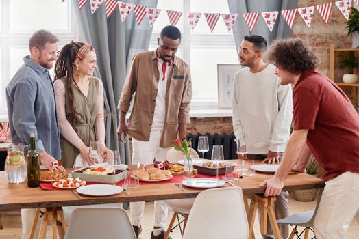 A group of people enjoying a Canadian-themed meal indoors, showcasing cultural diversity and celebration.