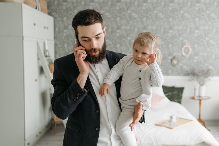 Man Talking To Someone While Carrying The Baby