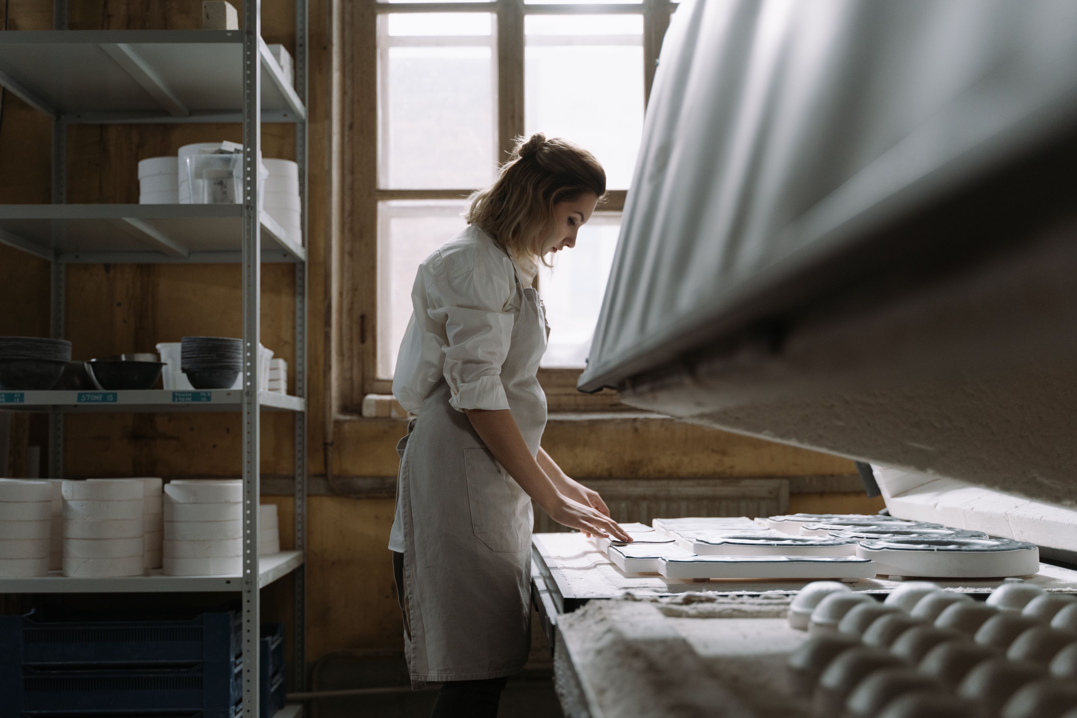 Woman Wearing Apron Touching the Ceramic Trays · Free Stock Photo