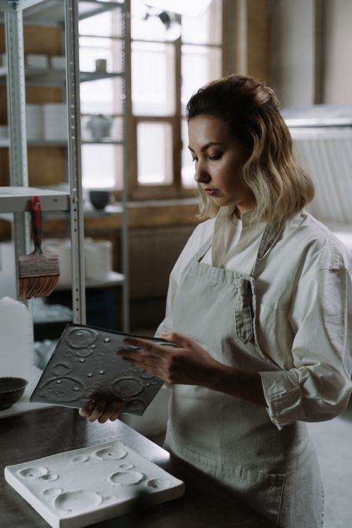 Free A craftswoman examining a glass piece in a manufacturing setting with natural light. Stock Photo