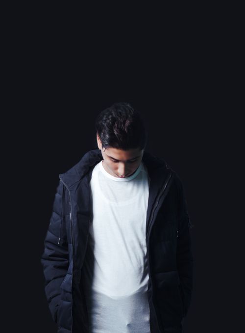Free A moody studio portrait of a man looking down, wearing a dark jacket and white shirt. Stock Photo