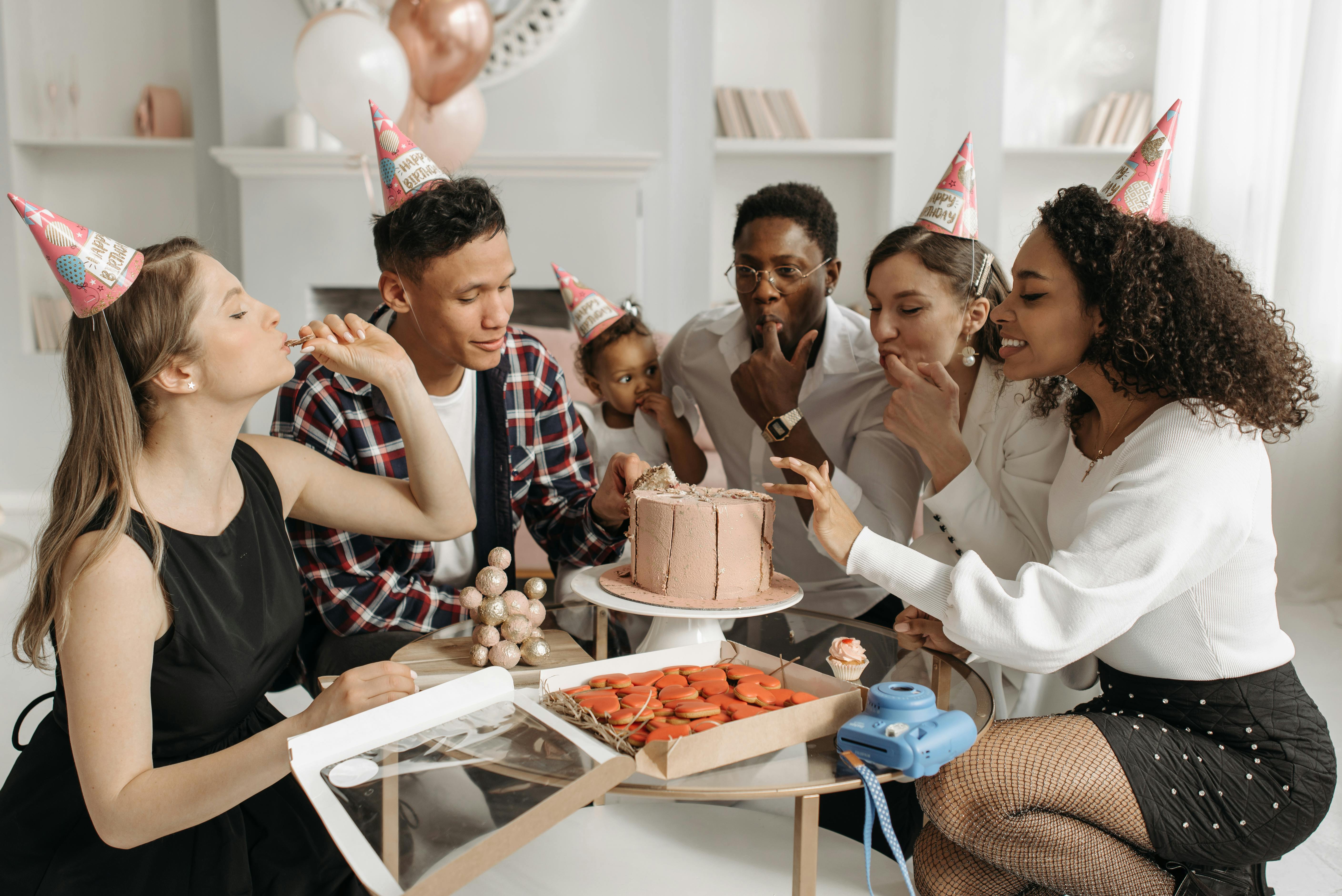 A joyful birthday celebration with a diverse family, featuring cake and party hats indoors.