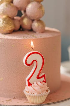 Celebratory pink cake with a number two candle, perfect for a birthday event.