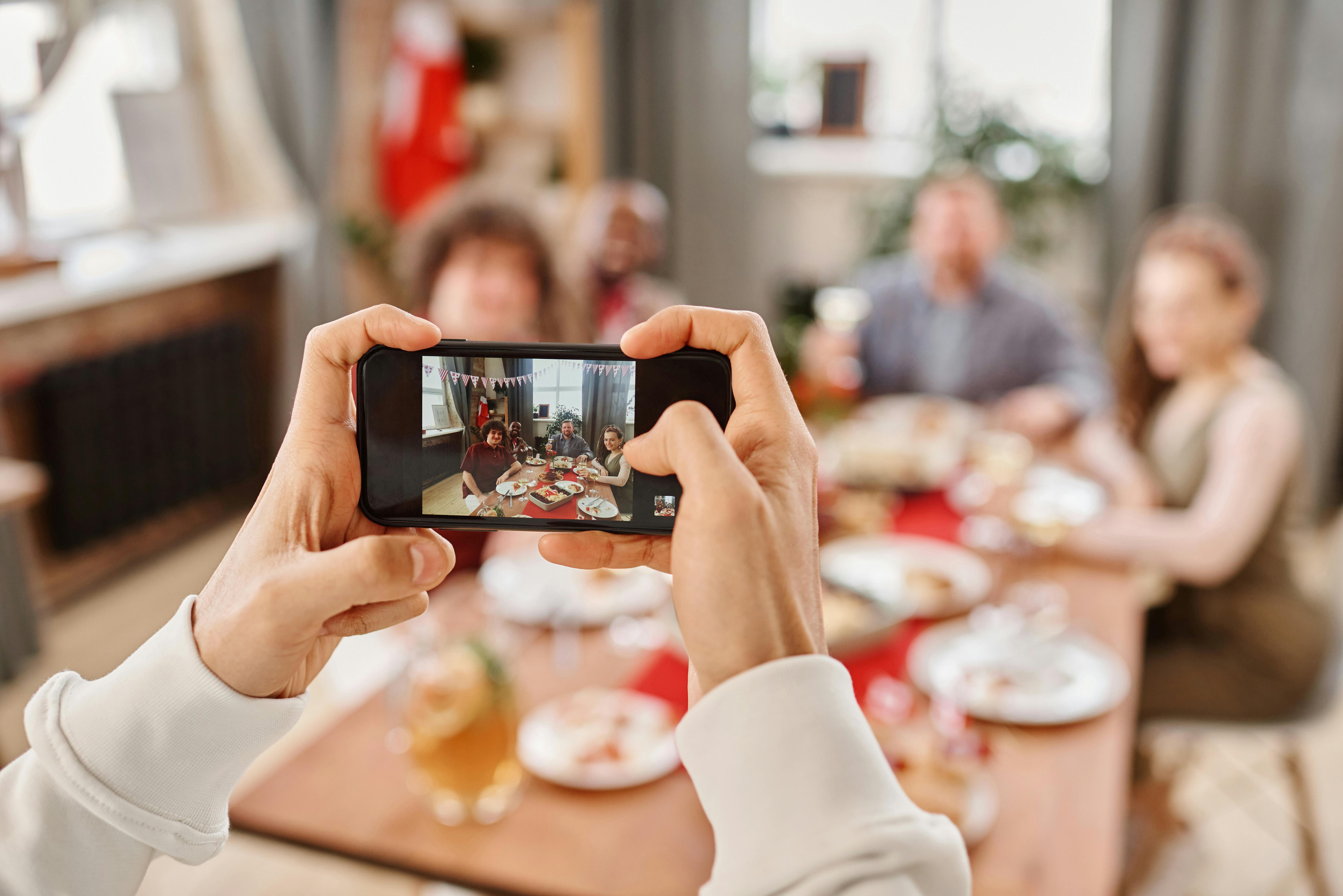 Free A smartphone captures a group enjoying a festive meal together indoors. Stock Photo