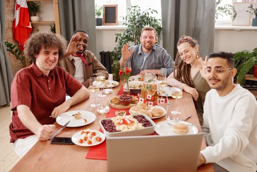 A group of friends sharing a joyful meal and engaging in a video call. Diverse, happy scene.