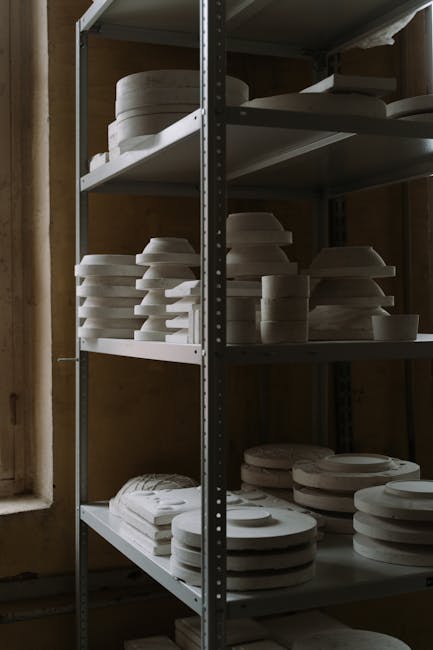 Organized clay kitchenware on shelves in a pottery factory offers a glimpse into the manufacturing process.
