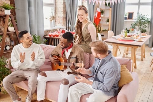 Free Group of friends enjoying music and conversation indoors, sharing a joyful moment together. Stock Photo