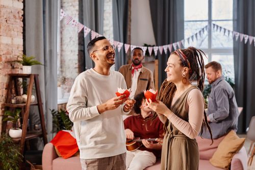 Free A diverse group of friends enjoying a lively indoor celebration with food and music. Stock Photo