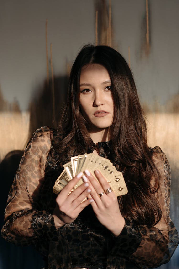 Asian Woman Holding A Deck Of Gold Cards