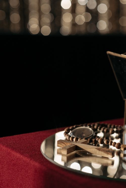 Free Wooden rosary and cross elegantly displayed on a reflective surface against a bokeh backdrop. Stock Photo