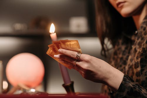 Free A Woman Beside a Lighted Candle Holding Gold Cards Stock Photo
