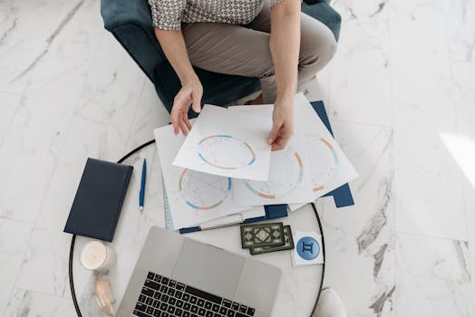 Astrology charts displayed with a laptop, deck of cards, and stationery on a marble floor.