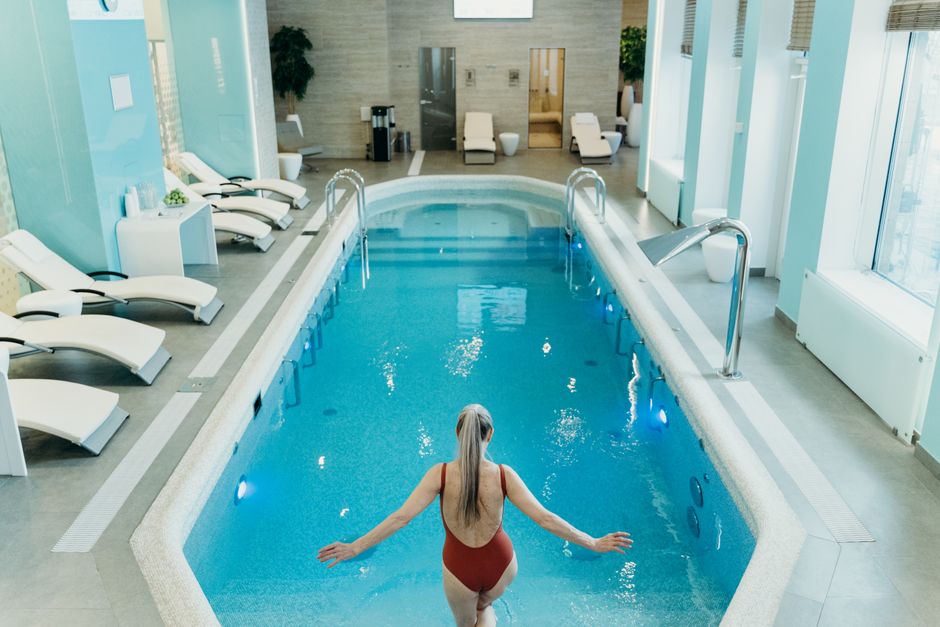 Cold Plunge Tubs: Benefits, Risks, and Best Options for Recovery A woman in a red swimsuit prepares to enter an elegant indoor pool at a luxurious spa.