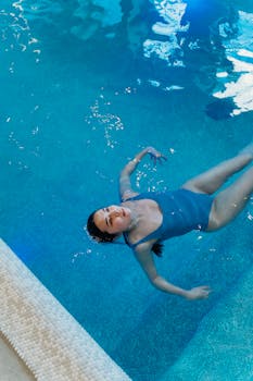 A woman enjoys leisure time floating in a serene indoor swimming pool.