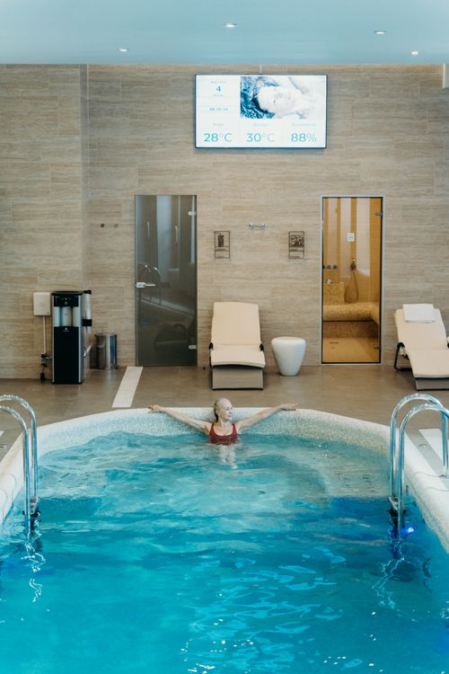 Free Woman enjoying leisure time in an indoor swimming pool, surrounded by modern amenities. Stock Photo