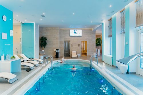 Free Luxurious indoor swimming pool in a modern spa with lounge chairs and soft lighting. Stock Photo