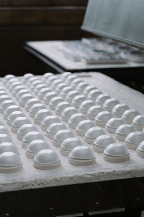 Free White mini mousse cakes on white marble countertop in confectionery industry on blurred background in daylight Stock Photo