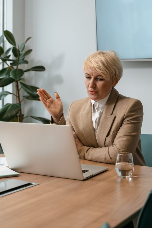 Free Businesswoman in office on a video call, engaging with a laptop. Stock Photo