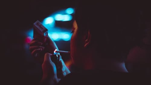 Free Man Lighting Up a Cigarette during Nighttime in Tilt Shift Lens Photograhy Stock Photo