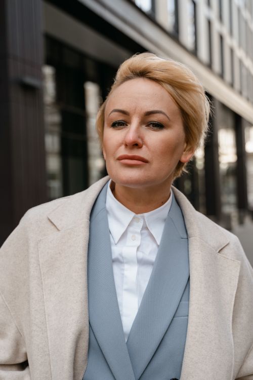 Free Portrait of a confident woman in a stylish coat standing outdoors against urban background. Stock Photo