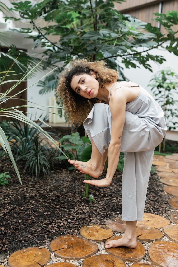 A Woman In Yoga Pose Standing Bending Forward With Knee To Chest