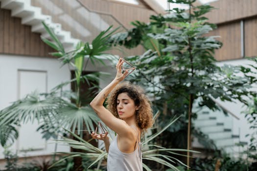 Artistic portrait of a woman posing indoors with a geometric object and lush greenery.