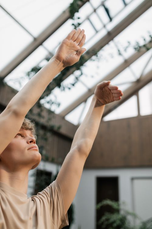 Free A young man in casual attire making a hand gesture upwards in a modern indoor setting. Stock Photo