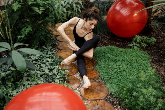 Woman practicing yoga amidst nature with exercise balls in a tropical garden setting.