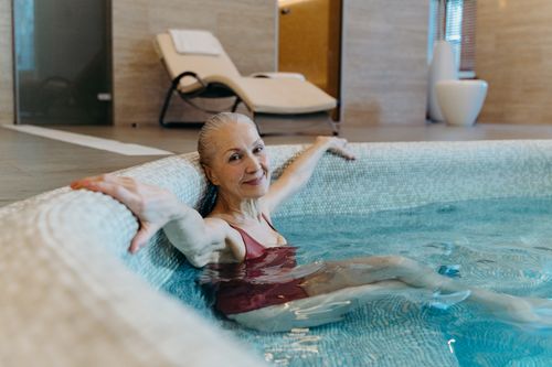 Free Elderly woman enjoying leisure time in an indoor pool, promoting healthy lifestyle and relaxation. Stock Photo