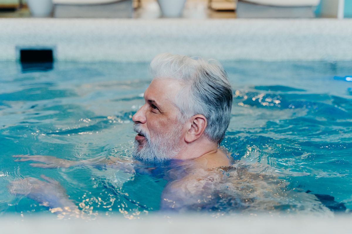 Bearded older man exercising in a swimming pool