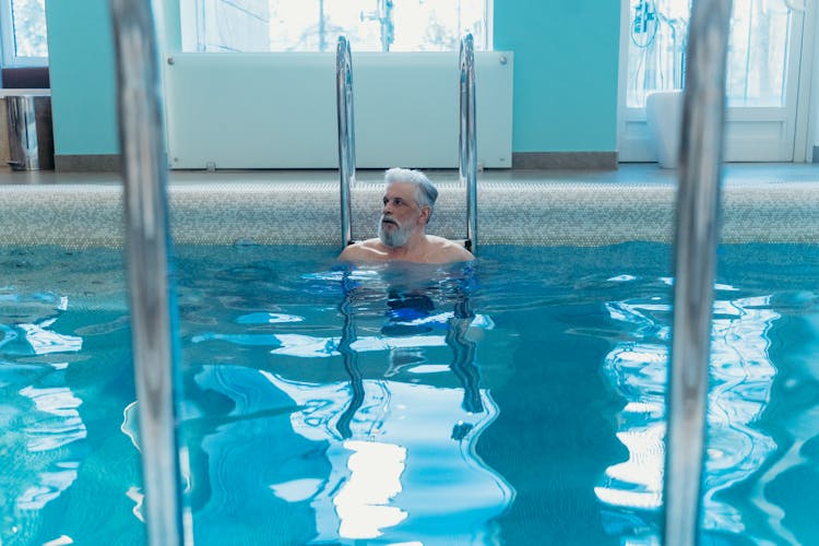 Bearded Man In The Swimming Pool Beside The Metal Ladder